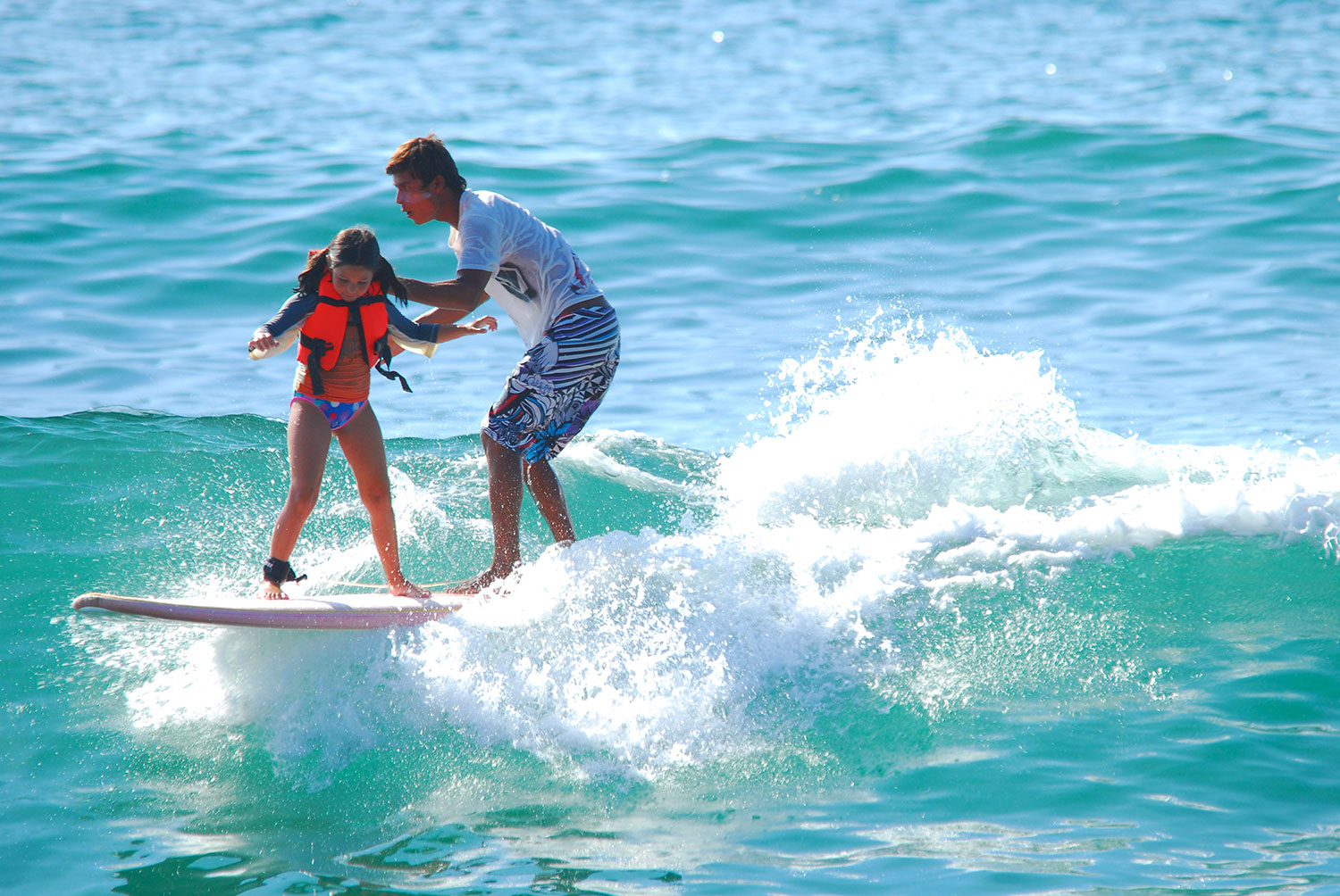 Instructor y niña surfeando