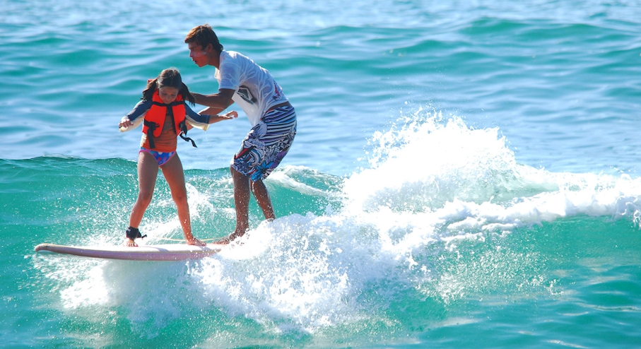 Instructor y niña surfeando