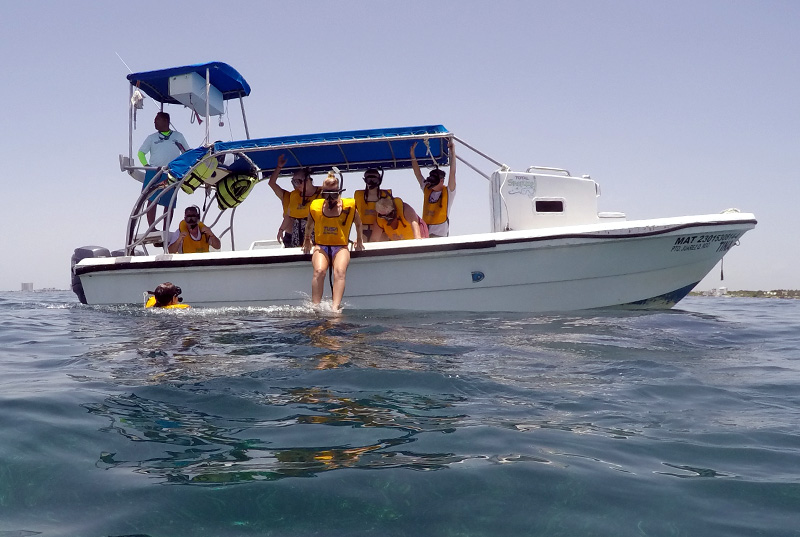 Grupo de viajeros con chalecos salvavidas en lancha de snorkel en aguas del Caribe en Cancún