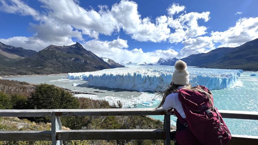 Mujer turista mirando el glaciar Perito Moreno desde las pasarelas en tour Denomades