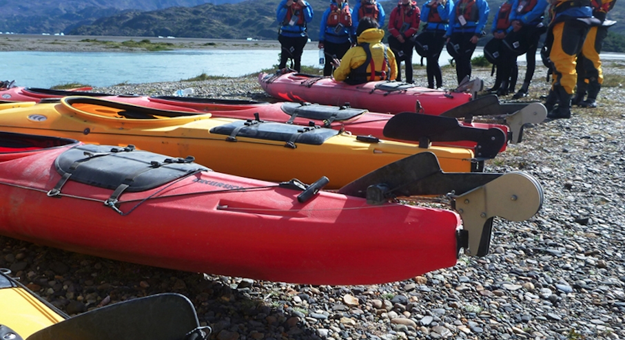 turistas recibiendo instrucciones de la guía para navegar en kayak por el lago grey