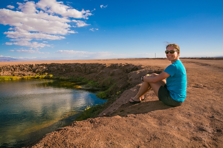 Una mujer sentada frente a la laguna cejar en San Pedro de Atacama