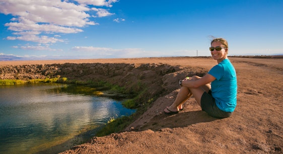 Una mujer sentada frente a la laguna cejar en San Pedro de Atacama