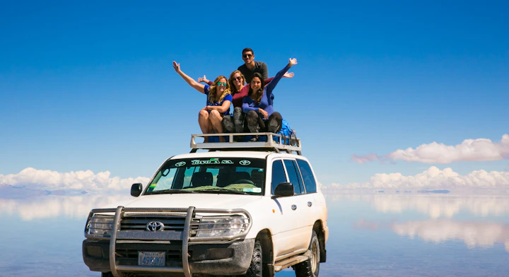 Personas sobre un Jeep en el Salar de Uyuni con efecto espejo.