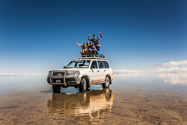 Personas sobre un Jeep en el Salar de Uyuni con efecto espejo.