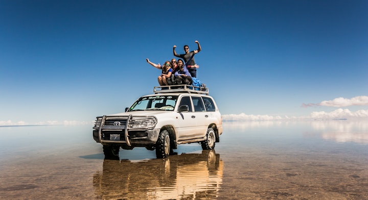 Personas sobre un Jeep en el Salar de Uyuni con efecto espejo.