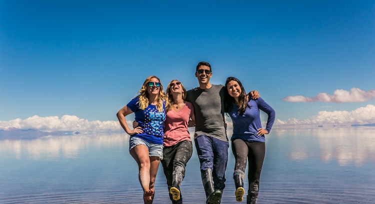 Personas sonriendo en el Salar de Uyuni con efecto espejo.