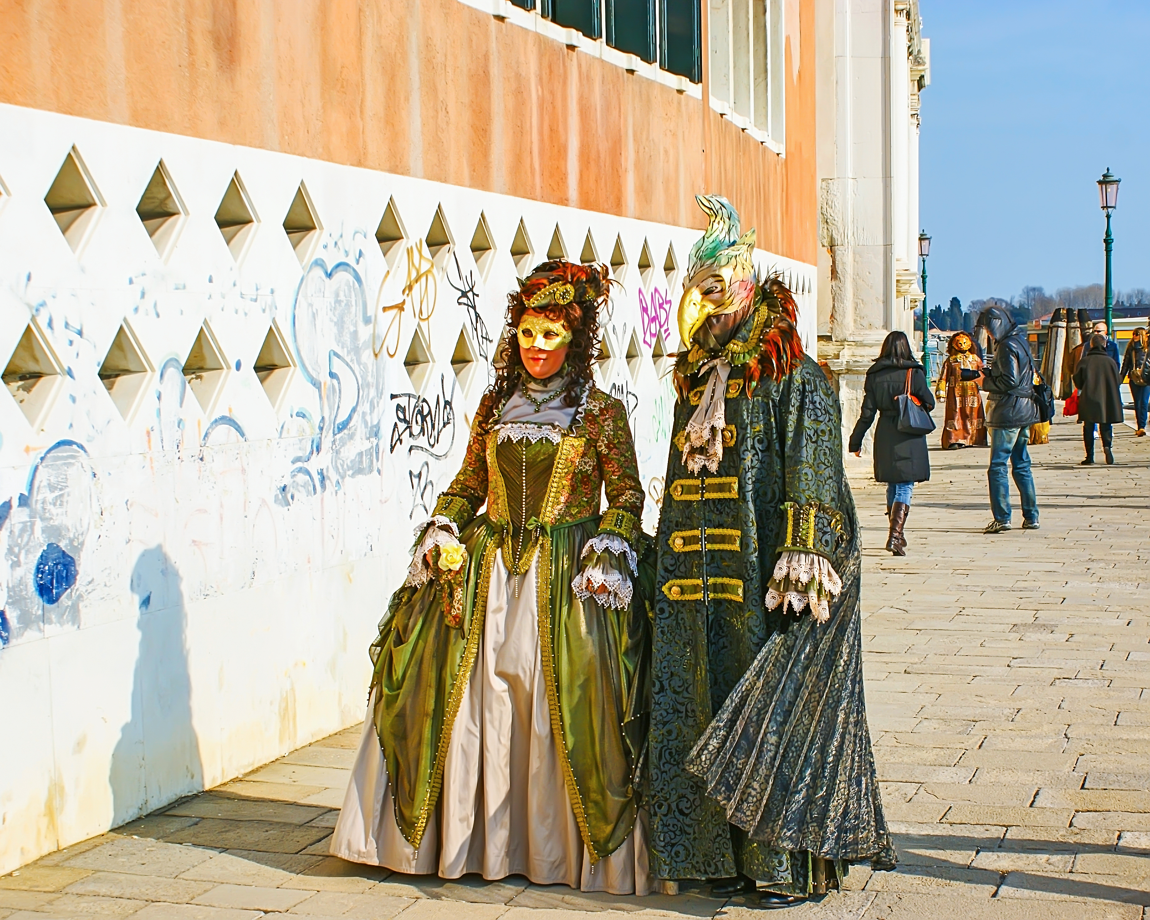Personas caminando con máscaras del Carnaval de Venecia